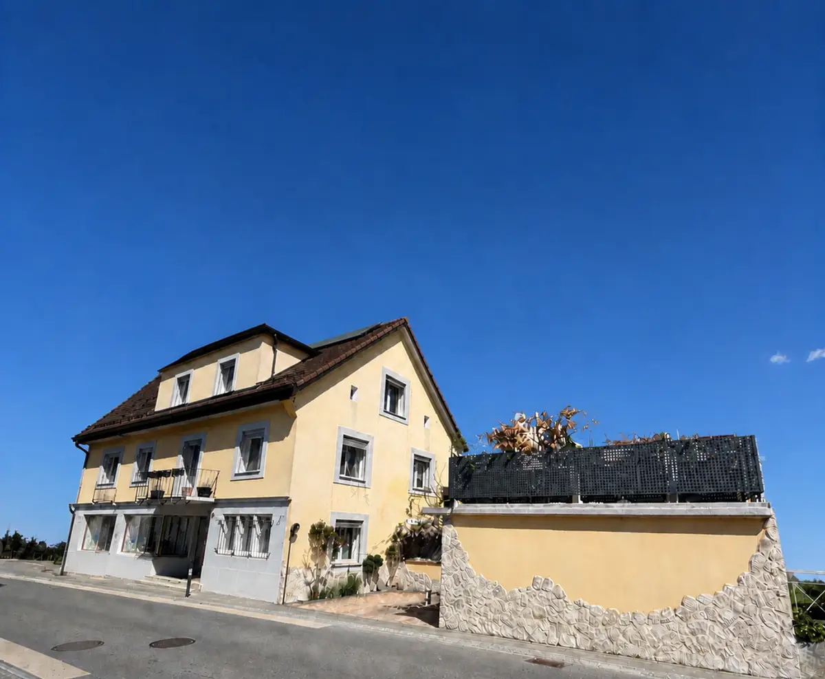 Immeuble de 2 appartements, un local commercial – 2 chambres- 2 places de parc et un garage/ Terrasse au centre du village
