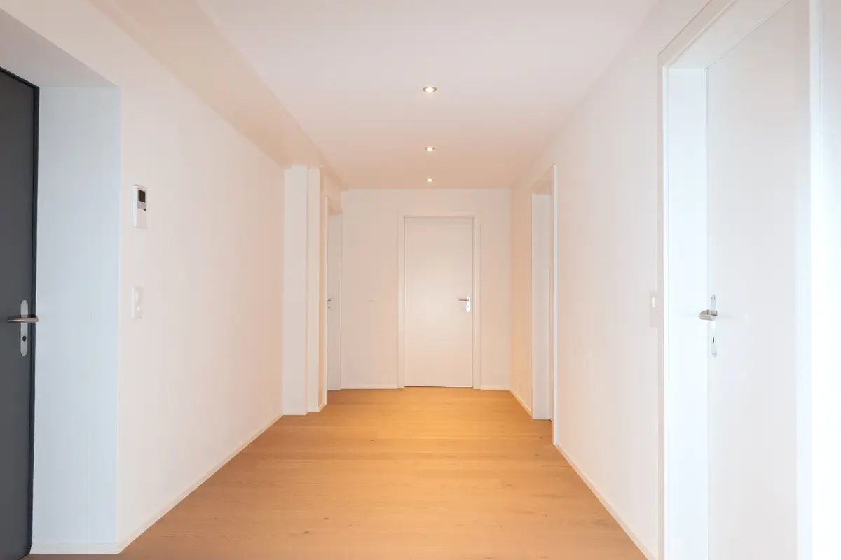 Heller Korridor mit Holzboden und mehreren Türen.