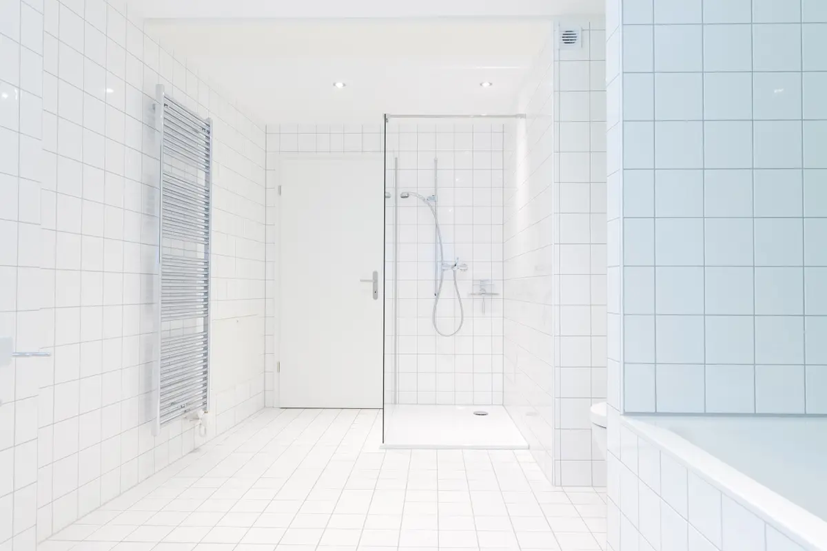 Modernes weiß gefliestes Badezimmer mit Dusche und Badewanne.