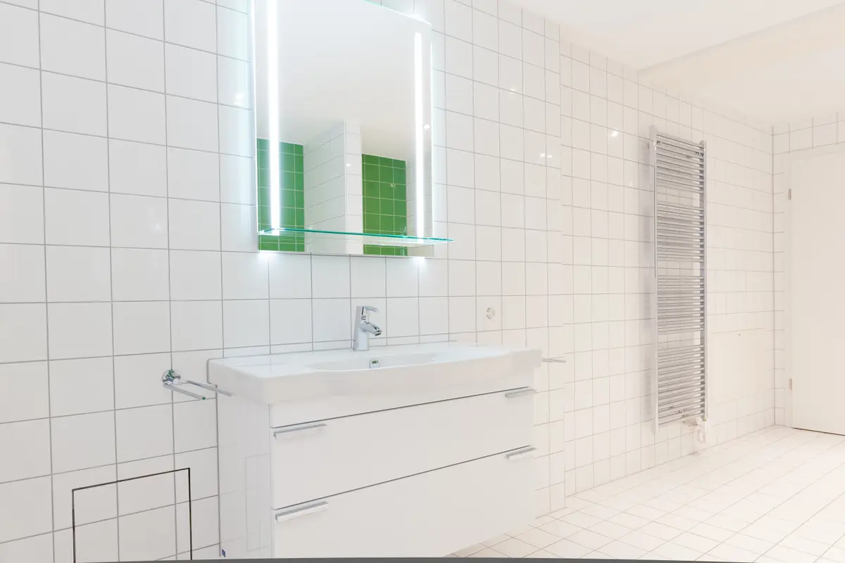 Modernes Badezimmer mit beleuchtetem Spiegel und weißem Waschbecken.